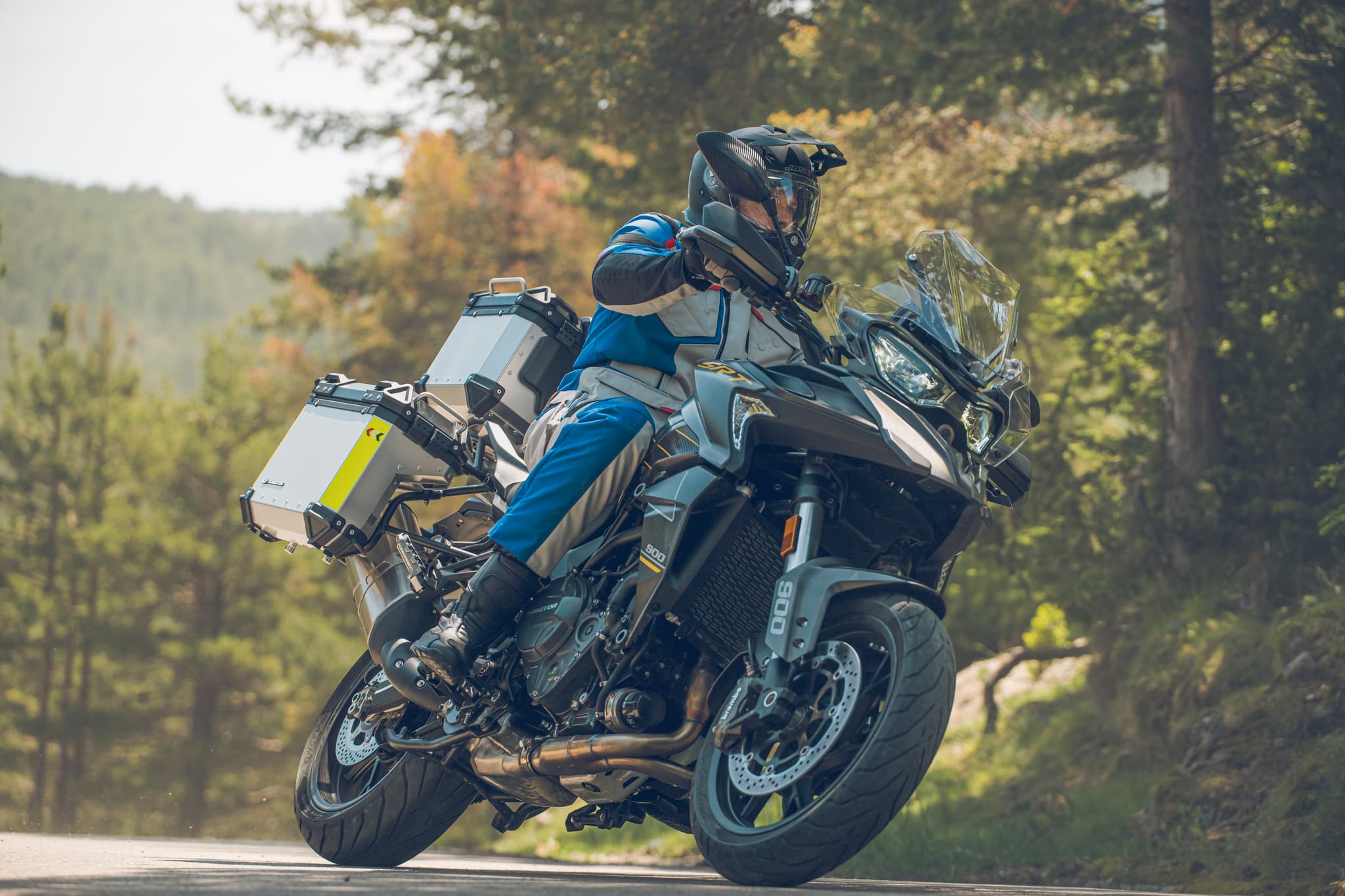 Motorista inclinando una trail cargada con maletas en una carretera de montaña