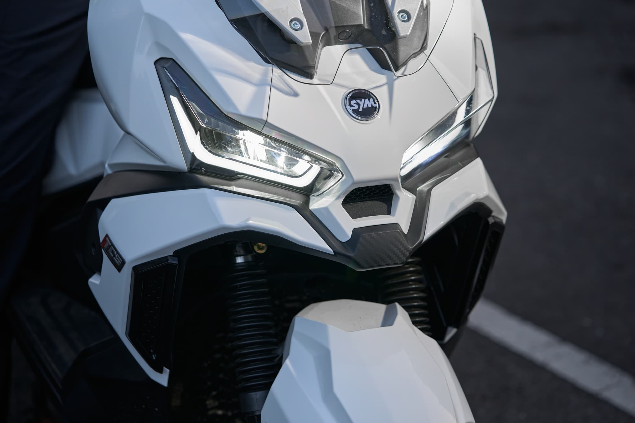 Frontal de la moto SYM ADX 125 ABS TCS blanca con luces LED encendidas
