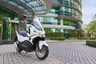 Scooter SYM ADX 125 ABS TCS blanca aparcada frente a un edificio moderno