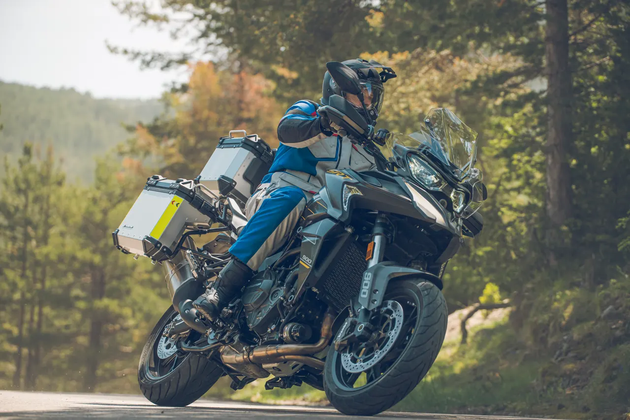 Motorista inclinando una trail cargada con maletas en una carretera de montaña